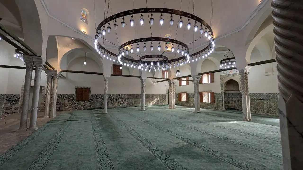 Interno sontuoso di una sala con colonne e un grande lampadario decorativo.