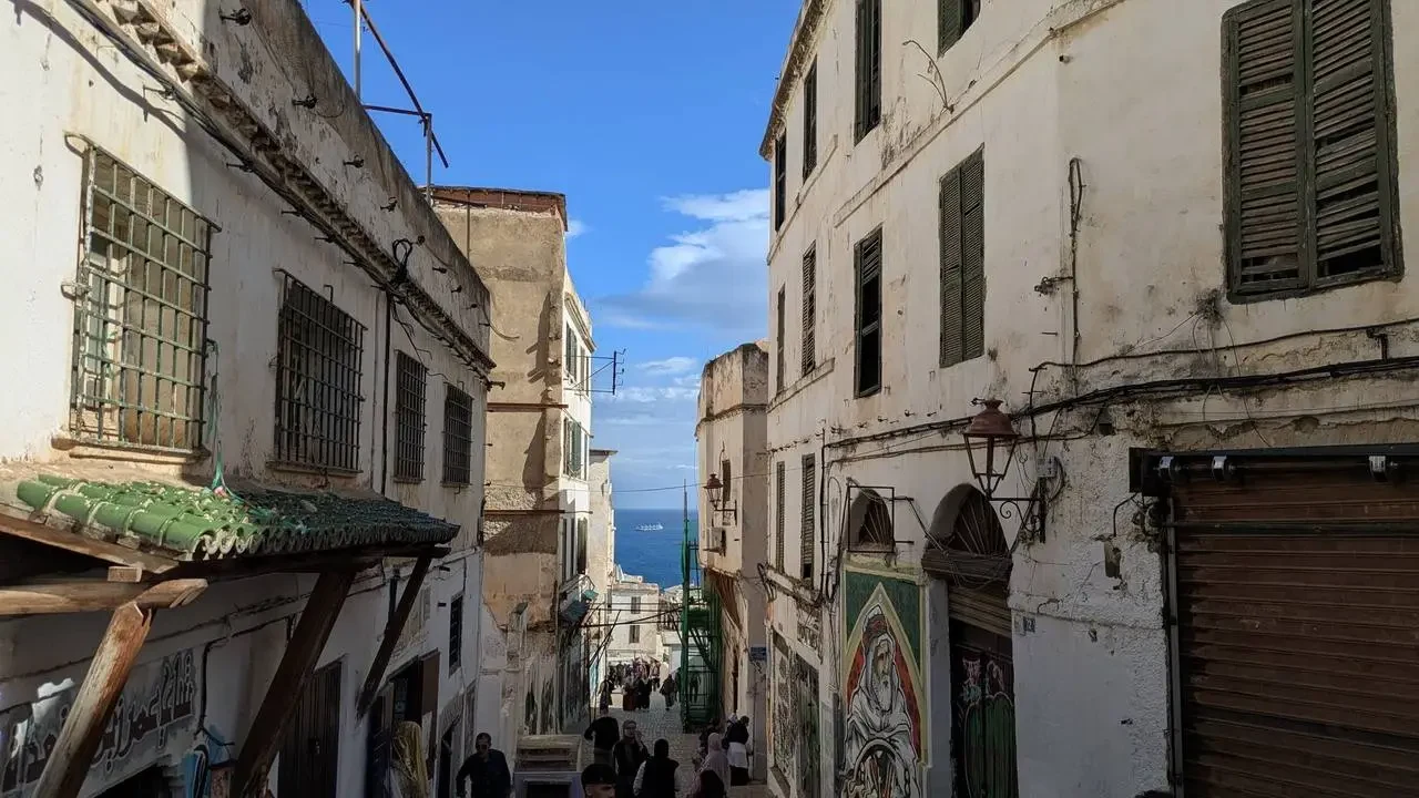 Vista della Casbah di Algeri con edifici storici in pietra e facciate chiare sotto un cielo azzurro.