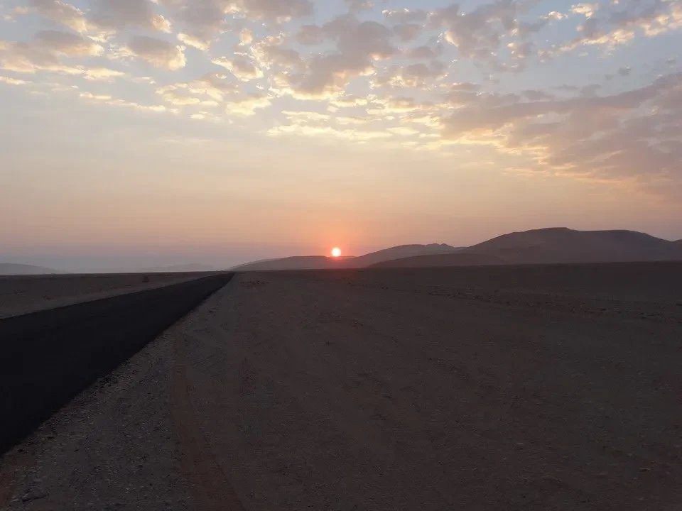 Un sentiero sterrato attraversa un paesaggio desertico al tramonto in Namibia.