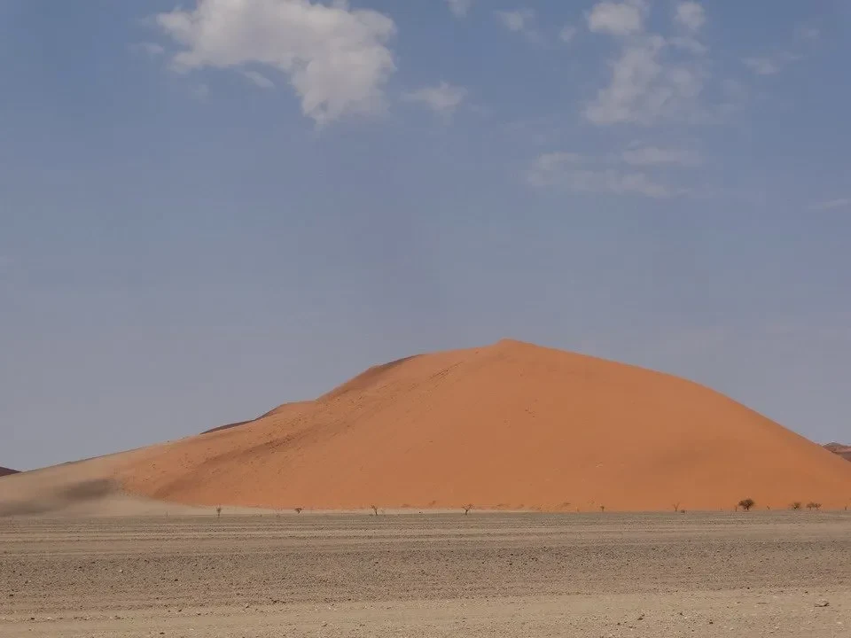 Un paesaggio desertico con dune rosse sotto un cielo azzurro.