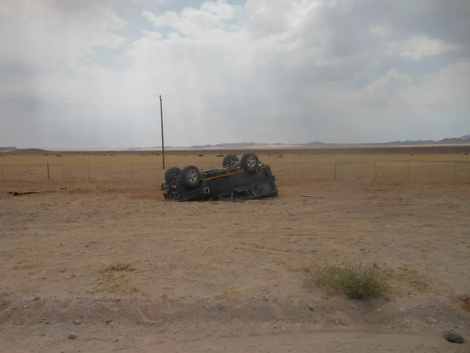 Un veicolo danneggiato è abbandonato in un paesaggio arido del Kalahari o della savana africana.