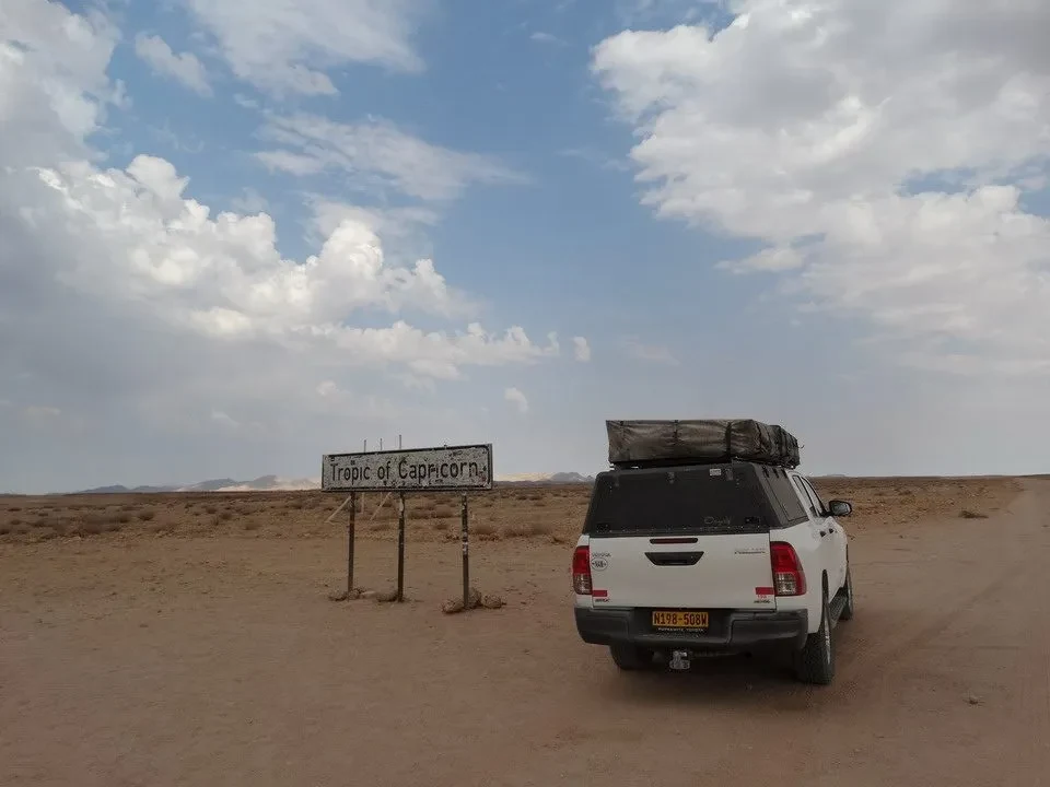 Un veicolo si ferma su un sentiero sabbioso in una vasta pianura africana.