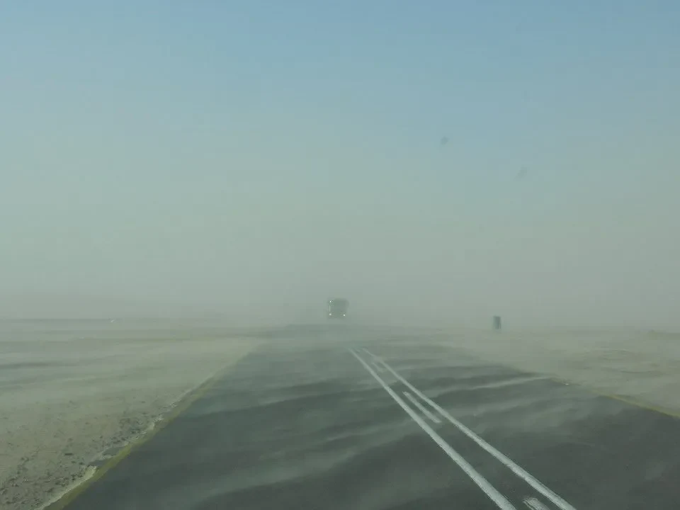 Una strada asfaltata si estende attraverso un paesaggio deserto e brumoso.