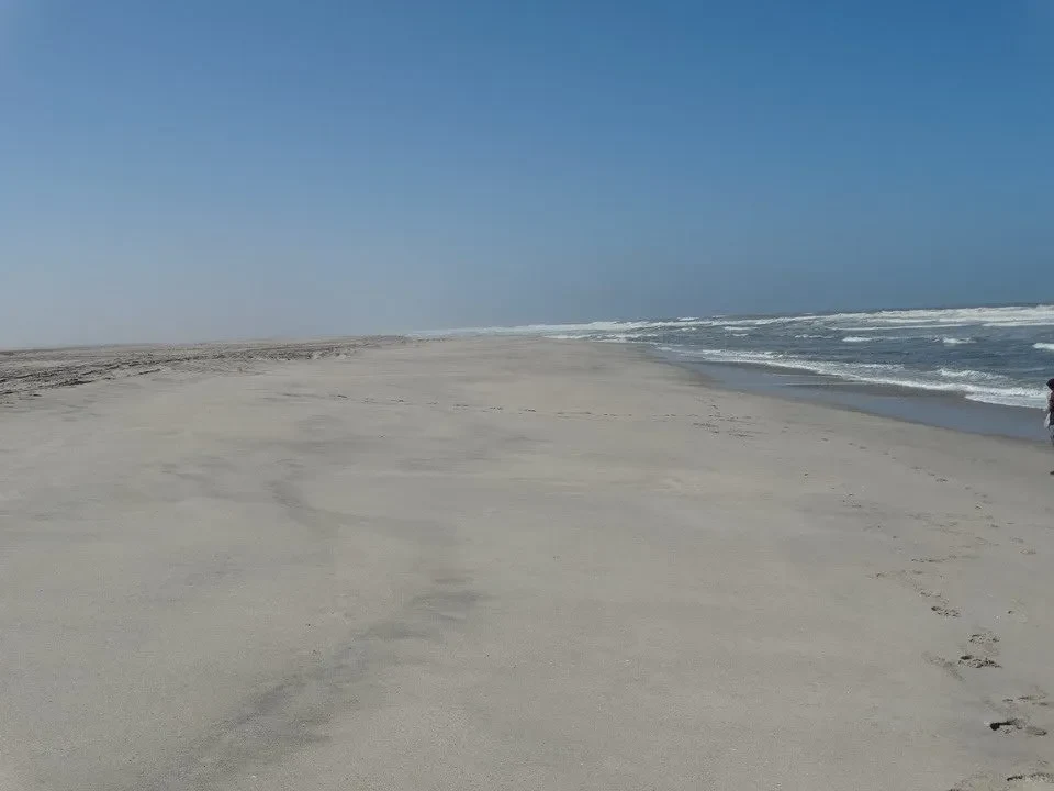 Una spiaggia sabbiosa si estende sotto un cielo azzurro e limpido.