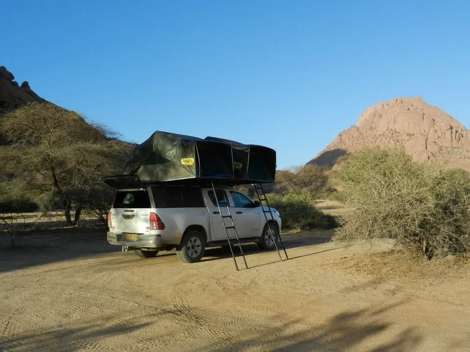 Un veicolo fuoristrada è parcheggiato su una strada sterrata in un paesaggio arido africano.