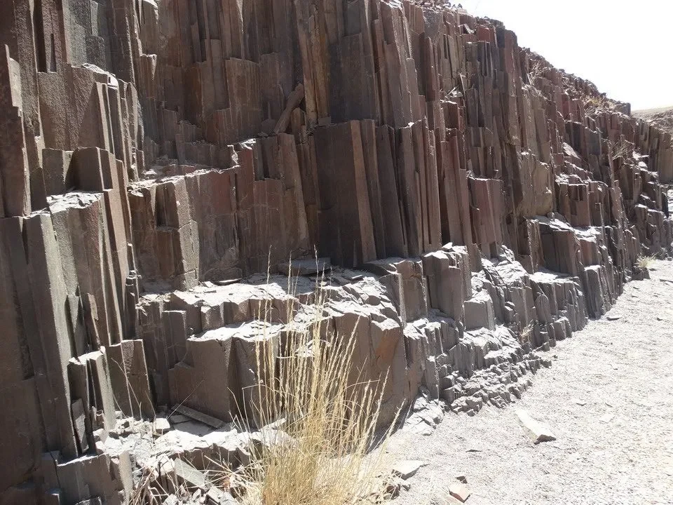 Formazioni rocciose stratificate e verticali lungo un paesaggio arido.
