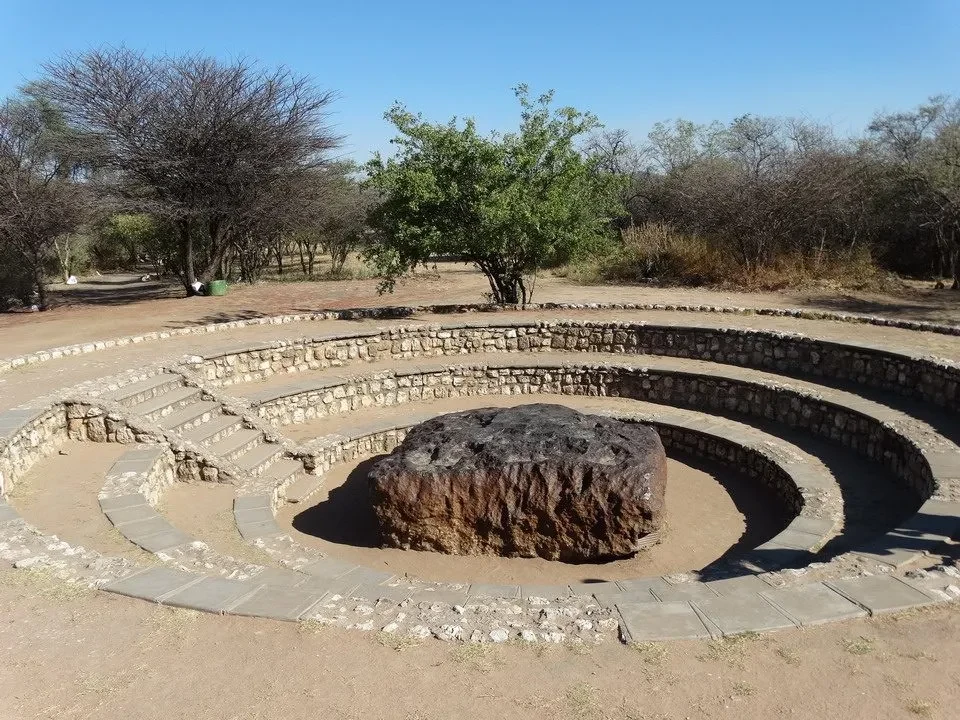 Una roccia scura è posta al centro di una struttura circolare in pietra all'aperto.