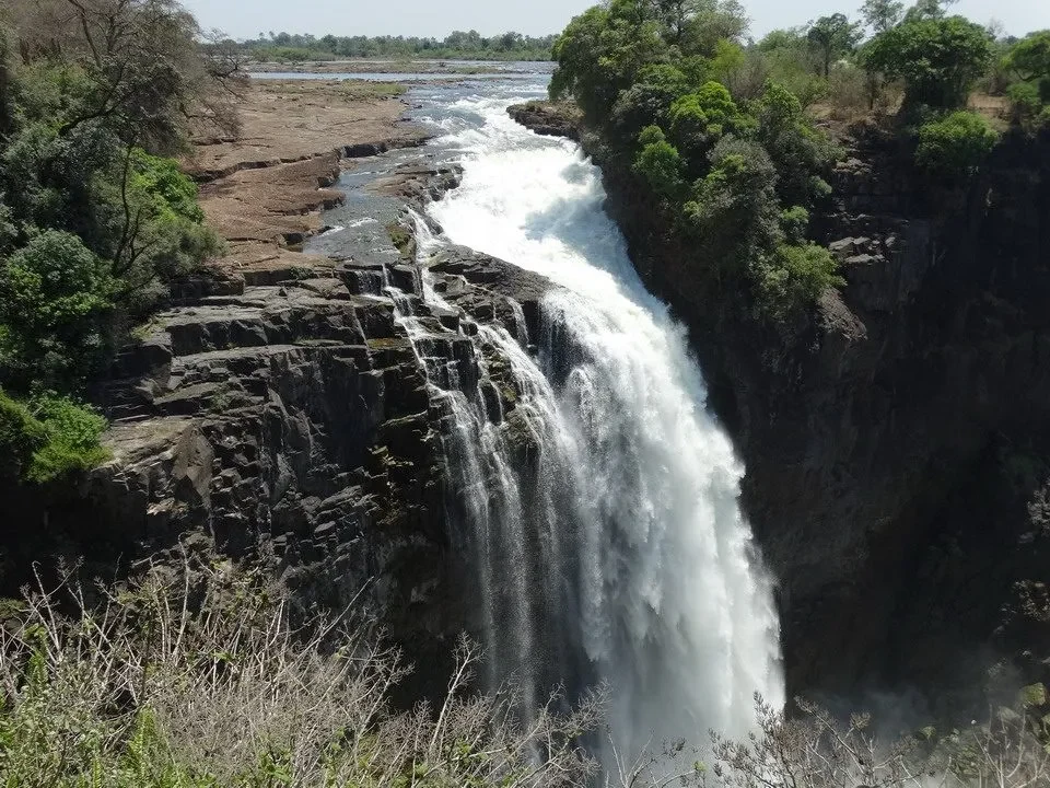Una cascata imponente scorre lungo una gola rocciosa in un paesaggio selvaggio.