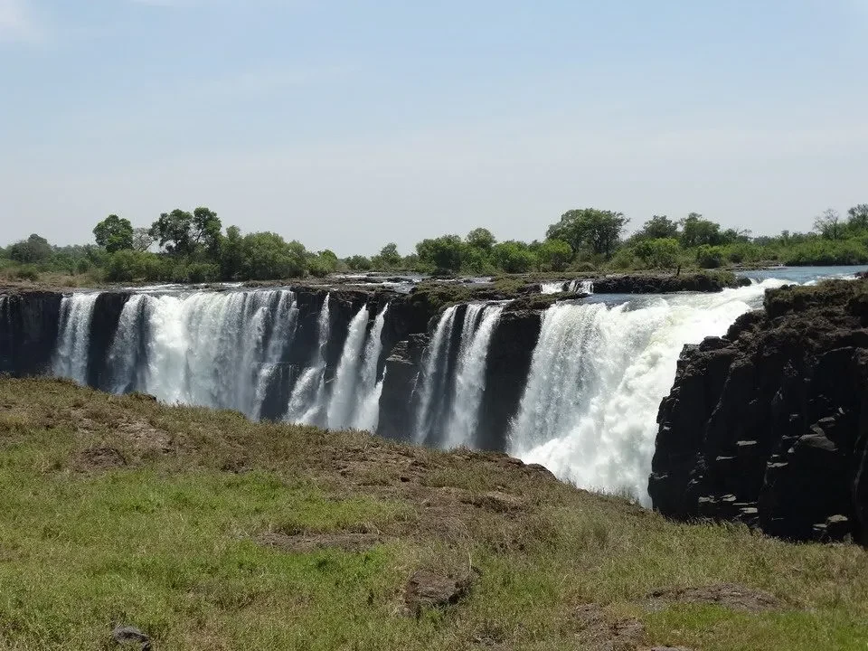 Cascata imponente attraversa la savana africana con acqua schiumosa. Cascata imponente attraversa la savana africana con acqua schiumosa.