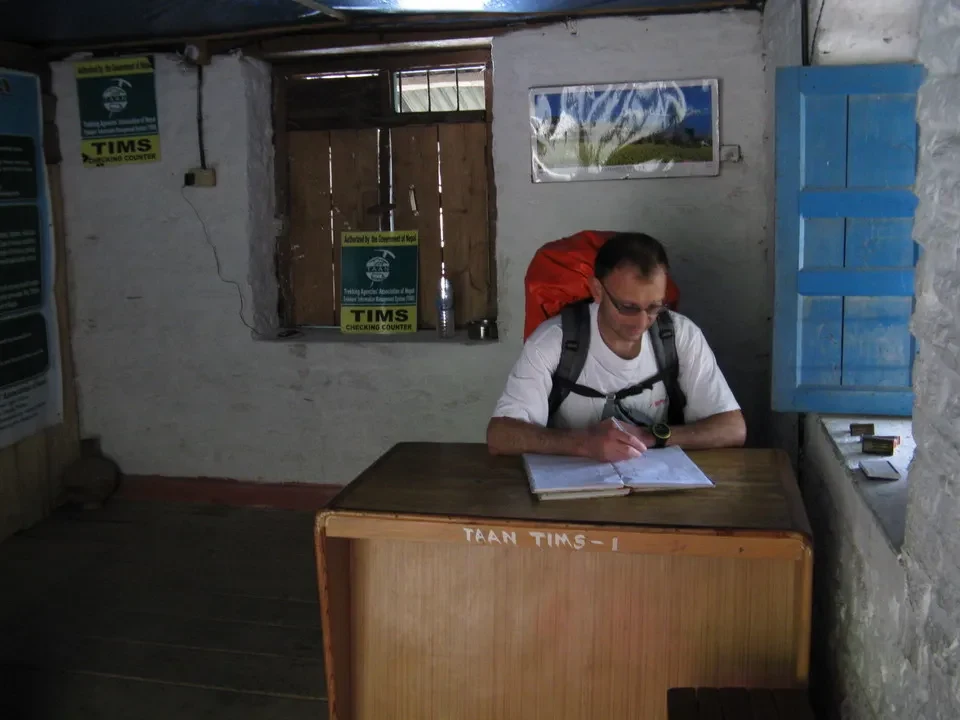 Un uomo firma documenti a un tavolo in un ufficio di confine nel Nepal o Tibet.