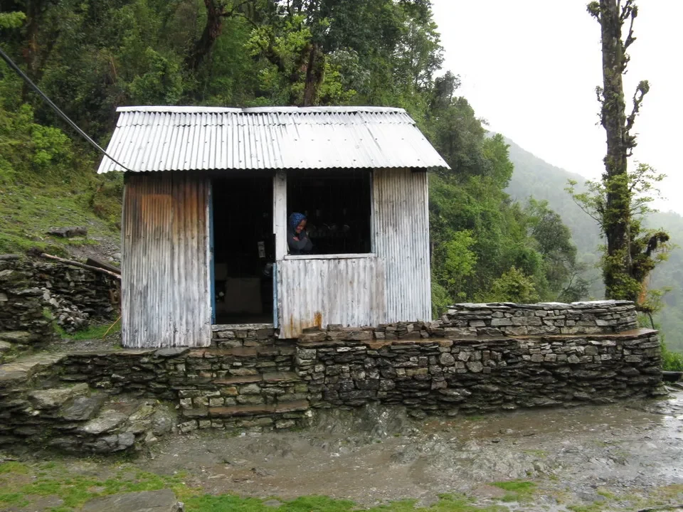 Un piccolo rifugio in legno con tetto metallico si trova in un paesaggio montano.
