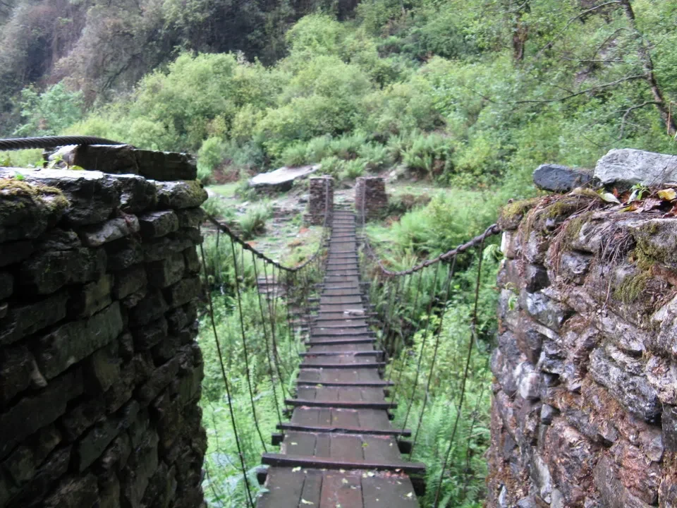 Ponte in pietra che attraversa un fiume boscoso in Nepal e Tibet.