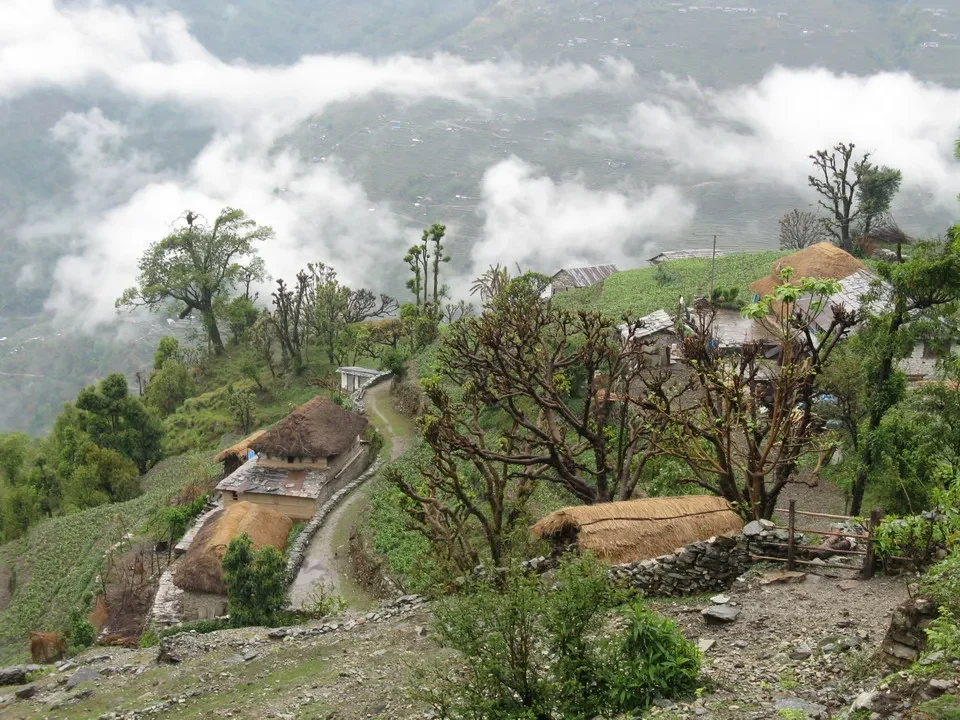 Paesaggio montano con abitazioni in Nepal o Tibet avvolte da nebbia.