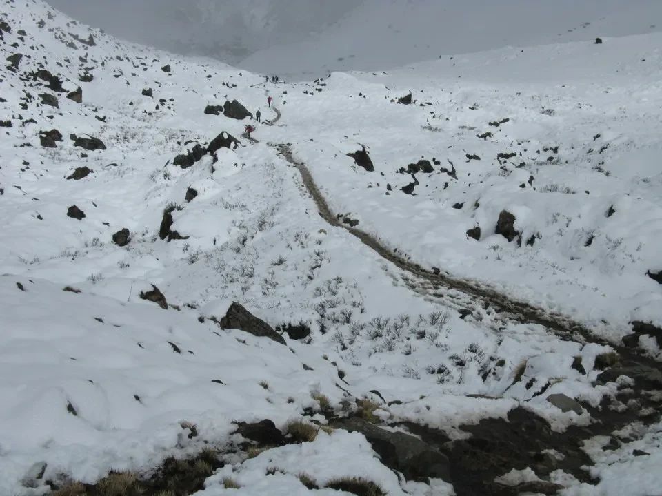 Un sentiero innevato attraversa un paesaggio montano innevato in Nepal o Tibet.