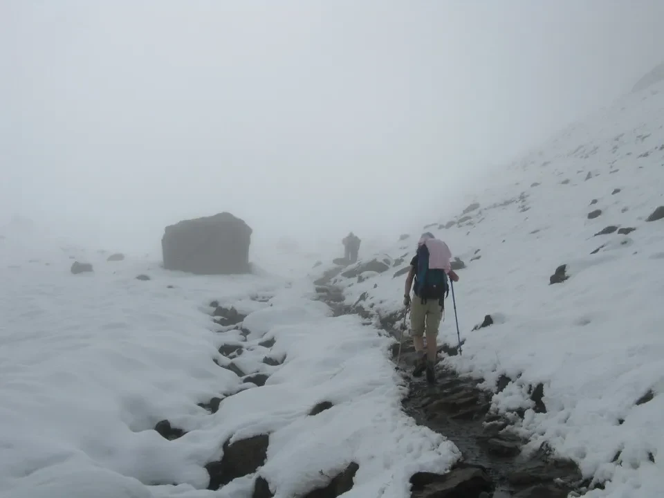 Un escursionista attraversa un letto di fiume innevato in montagna.