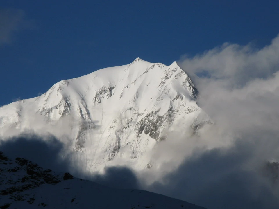 Una montagna innevata si staglia sopra le nuvole in un paesaggio himalayan.
