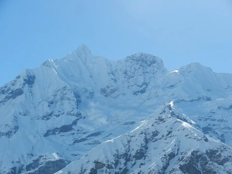 Catene montuose innevate si stagliano sotto un cielo azzurro.