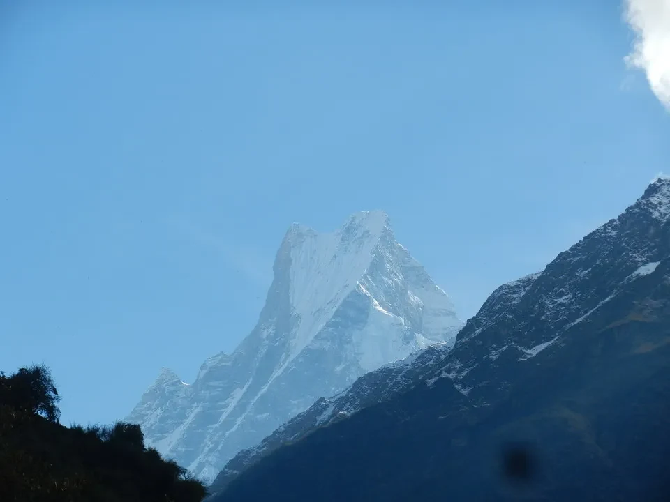Una maestosa catena montuosa innevata si staglia sotto un cielo azzurro.