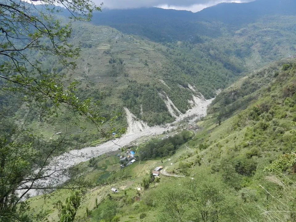 Paesaggio montano con un fiume che scorre attraverso una valle verdeggiante in Nepal e Tibet.