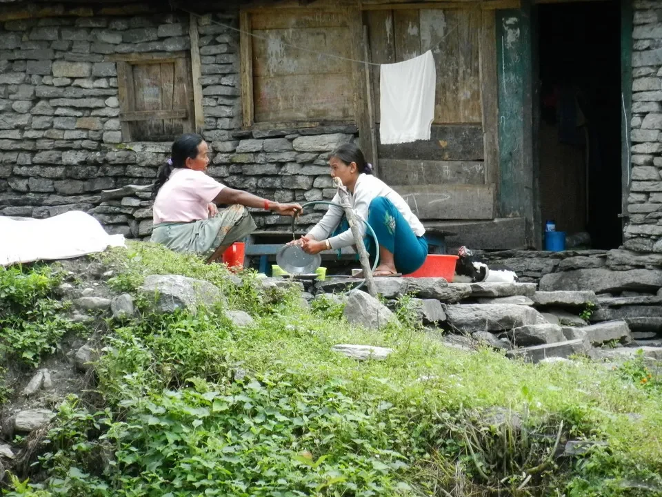 Due donne siedono all'aperto davanti a una struttura rustica in un ambiente montano.