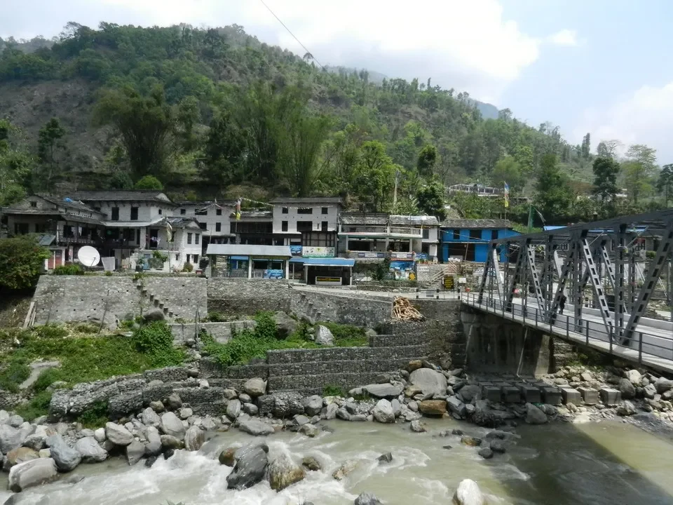 Paesaggio fluviale con edifici lungo la riva in Nepal o Tibet.