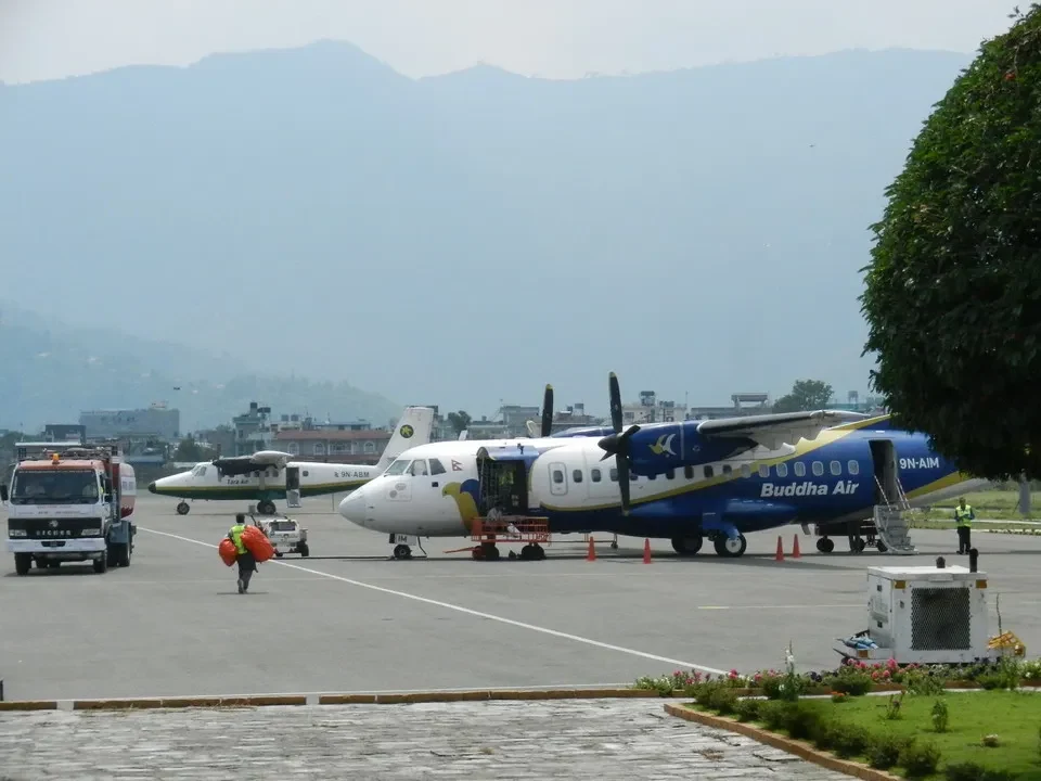 A small airplane is parked on the tarmac at an airport in the mountains of Nepal or Tibet.