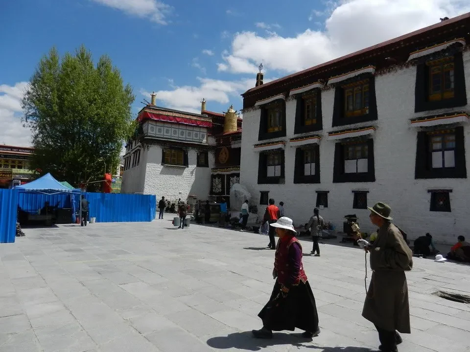 Un cortile aperto con edifici tradizionali in stile tibetano sotto un cielo azzurro.