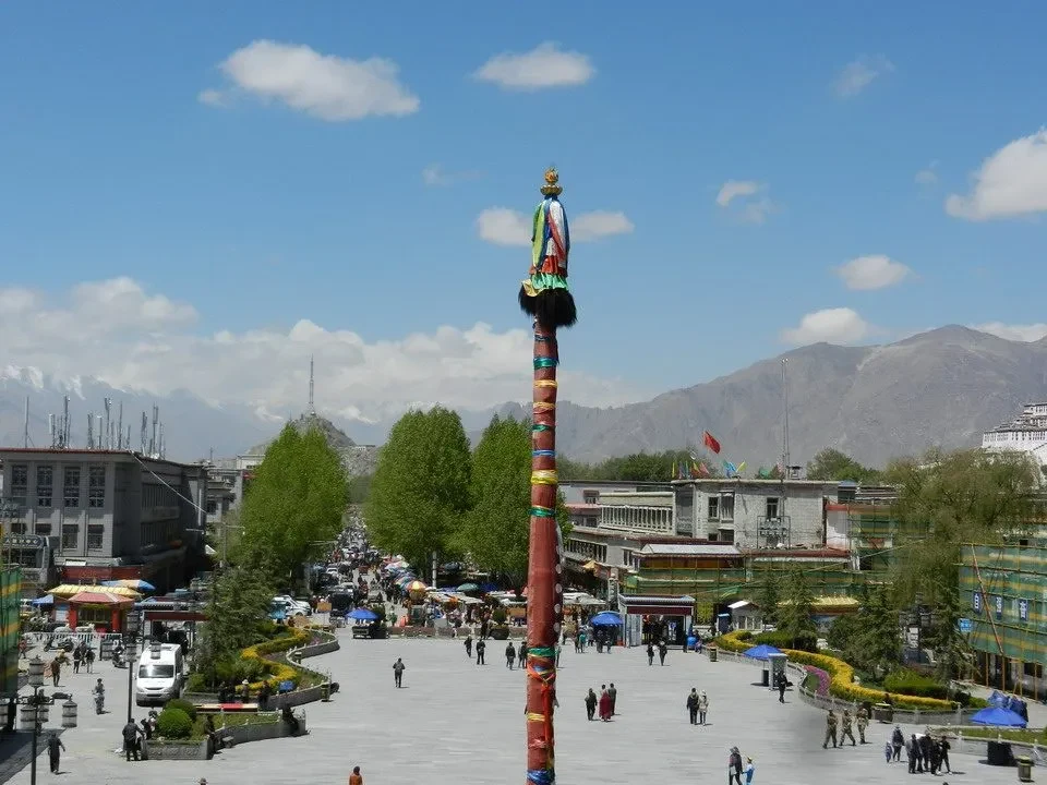 Una grande bandiera sventola in una piazza aperta con montagne sullo sfondo.