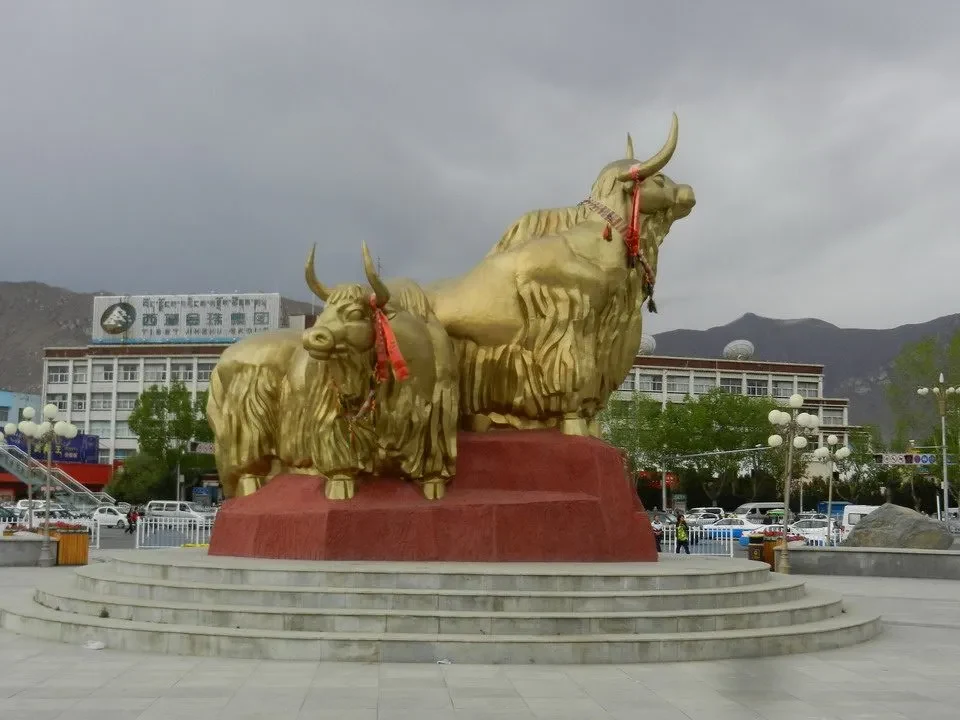 Statue di yak dorato in un contesto montano del Tibet o del Nepal.