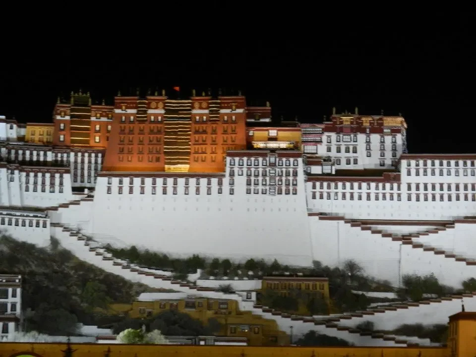 Il Palazzo del Potala di Lhasa è visibile di notte con montagne innevate sullo sfondo.