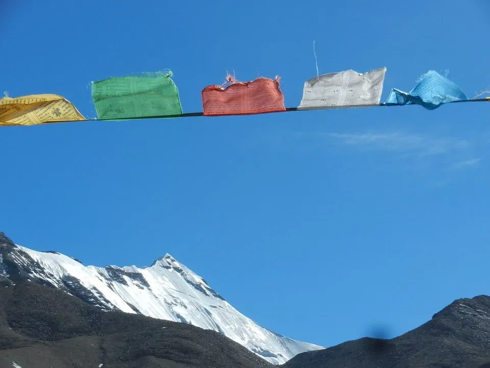 Paesaggio montano del Tibet con bandiere sventolanti contro il cielo blu.
