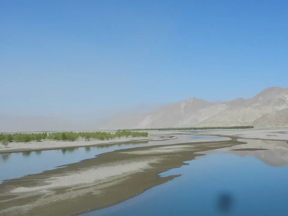 Un fiume ampio scorre attraverso un paesaggio montano arido in Nepal e Tibet.