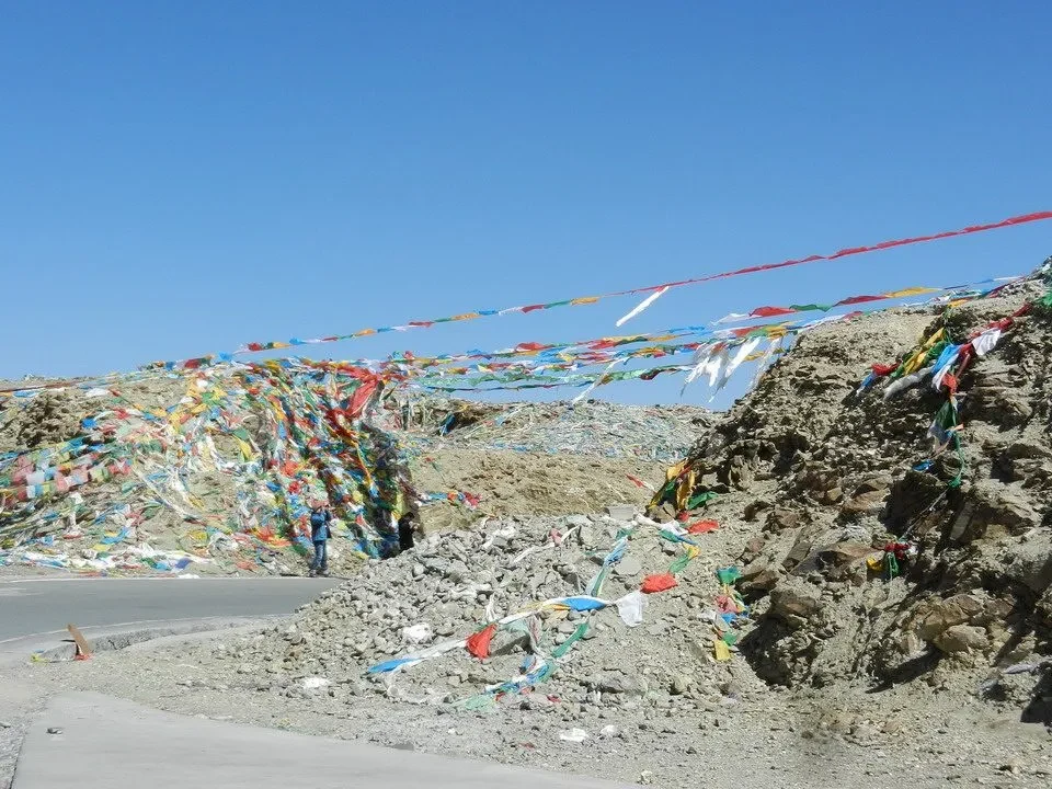 Un paesaggio montano in Nepal o Tibet mostra un fiume di striscioni colorati tra le rocce.