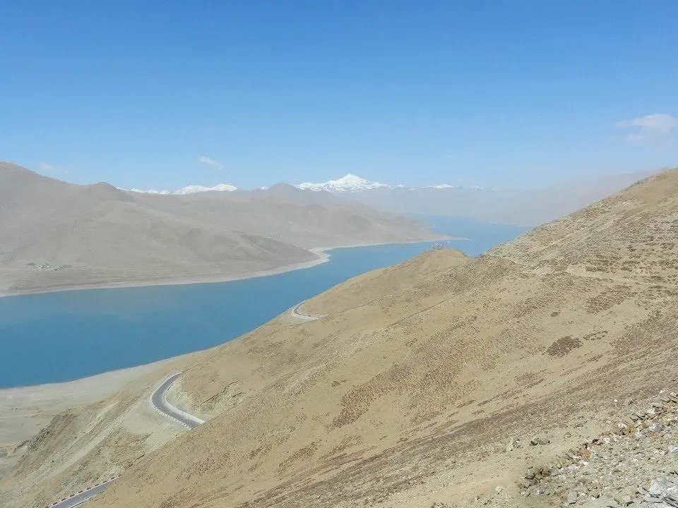 Un paesaggio montano vasto con un lago blu e montagne innevate in Nepal e Tibet.