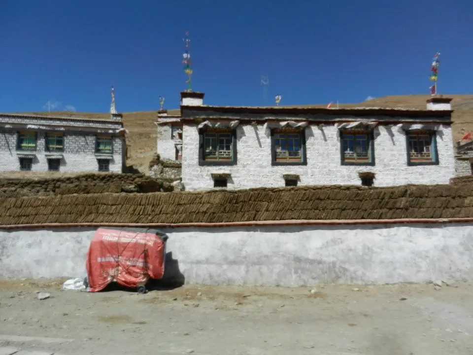 Edificio tradizionale in pietra con tetto di paglia in un paesaggio montano del Nepal e del Tibet.