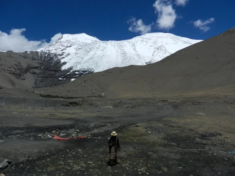 Un uomo cammina attraverso un paesaggio montano innevato in Nepal o Tibet.