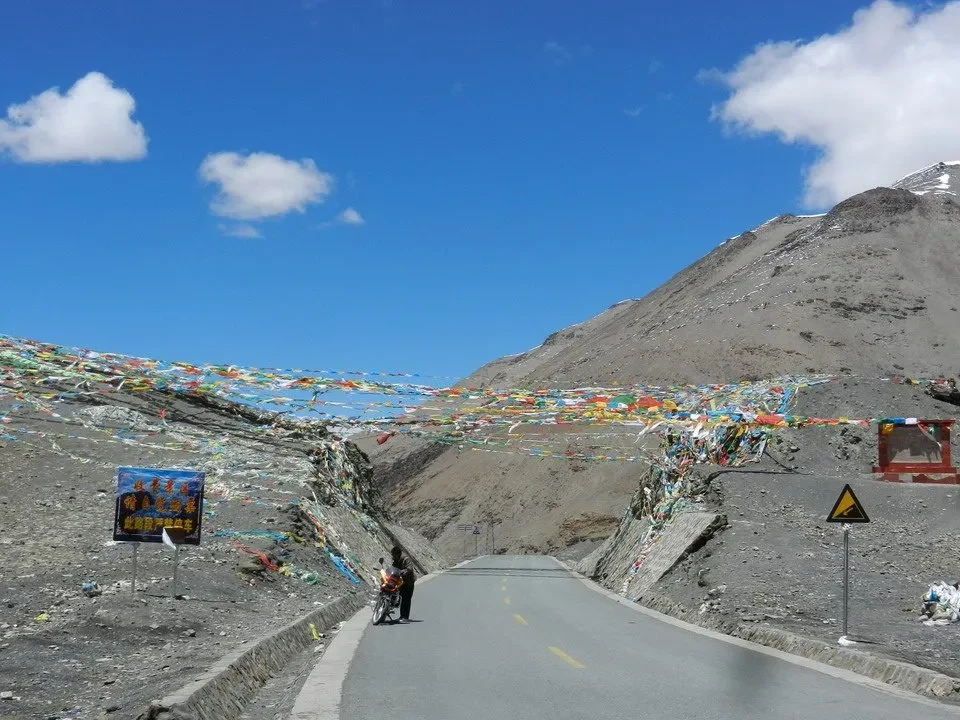 Una strada asfaltata attraversa un paesaggio montano innevato in Nepal o Tibet.