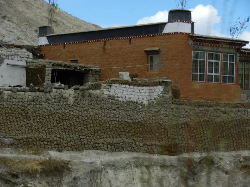 Un edificio in mattoni rossi con mura di pietra si staglia contro il cielo.