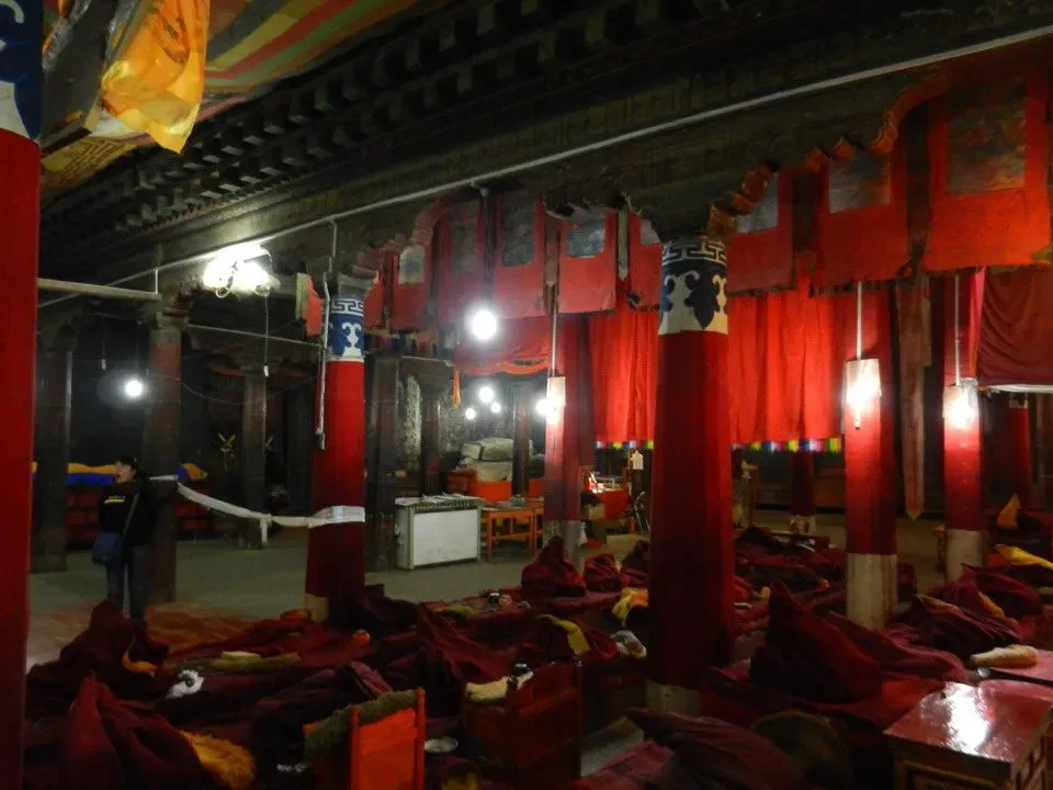 Interno del monastero di Gyantse, Nepal, mostra una sala interna decorata con tessuti rossi e strutture lignee.