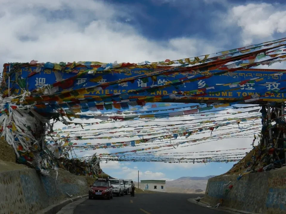 Una strada montuosa in Nepal o Tibet è decorata con striscioni colorati che si estendono sopra la carreggiata.