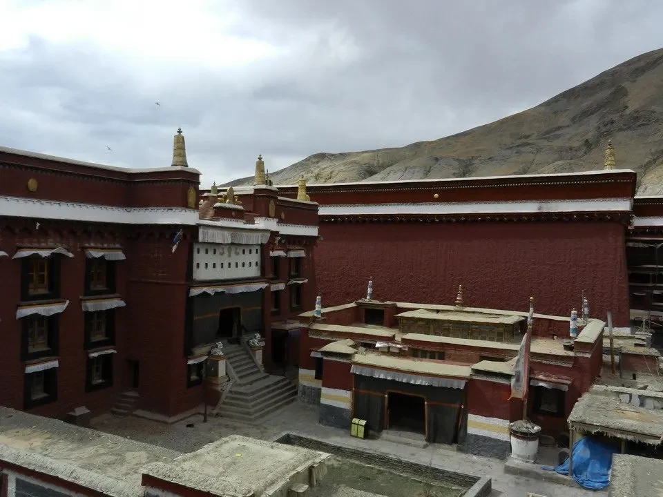 Monastero Sakya in Nepal o Tibet con mura rosse e paesaggio montano.