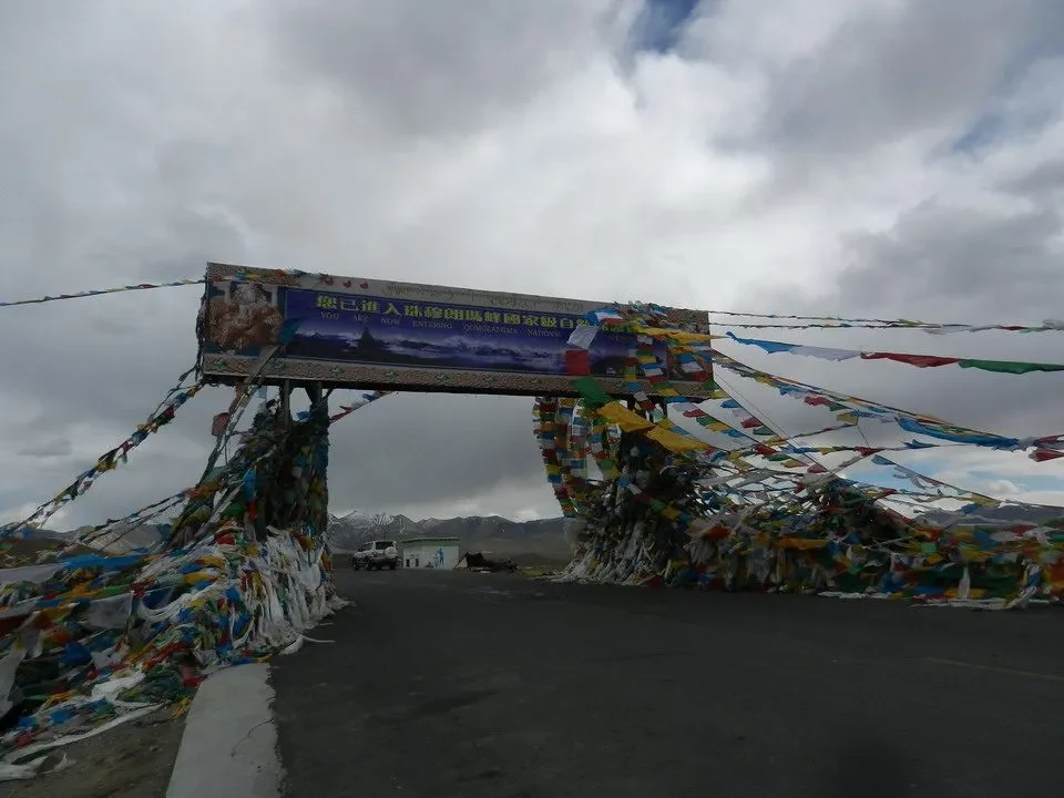 Un ponte decorato con bandiere attraversa una strada montuosa in Nepal e Tibet.