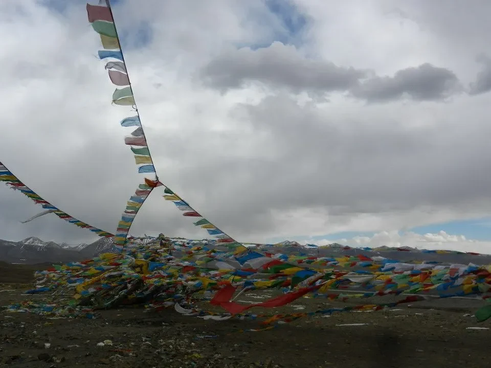 Una composizione di bandiere colorate si estende sul paesaggio montano del Nepal e del Tibet sotto un cielo nuvoloso.