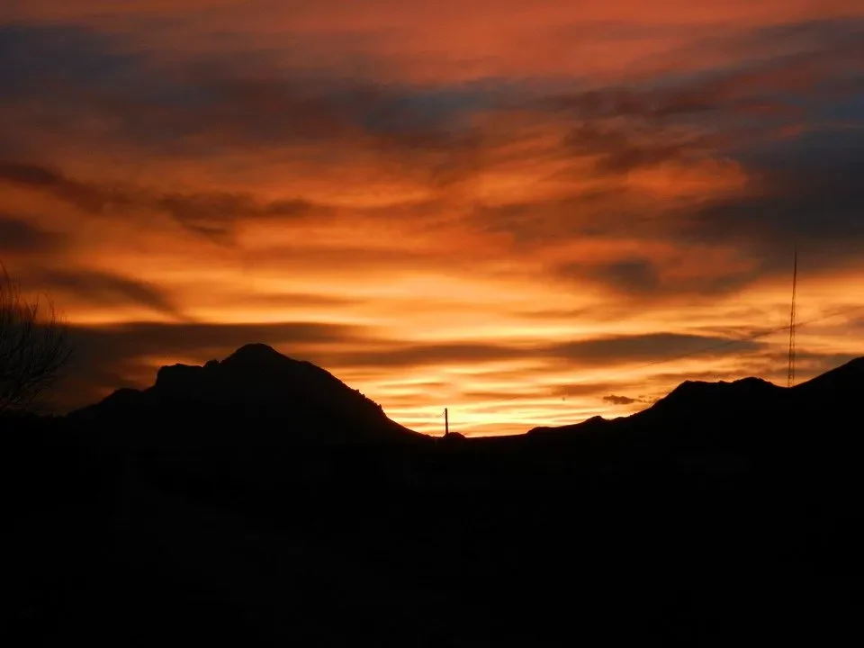 Silhouette montuose contro un cielo tramonto arancione e rosso intenso.
