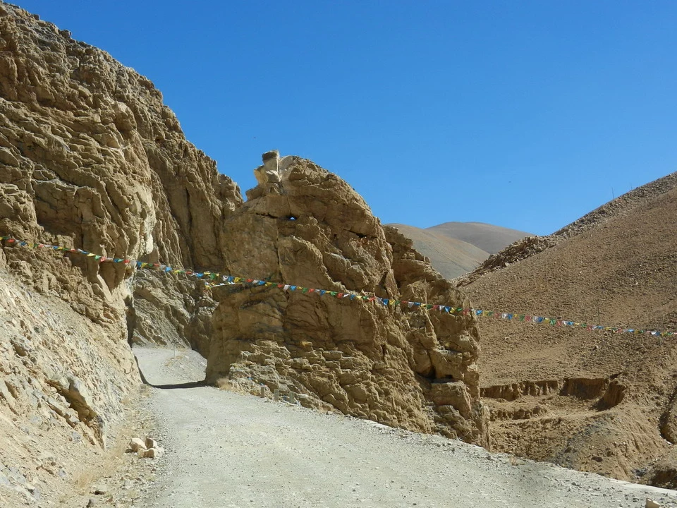 Un sentiero sterrato costeggia una gola rocciosa in un paesaggio montano del Nepal e del Tibet.