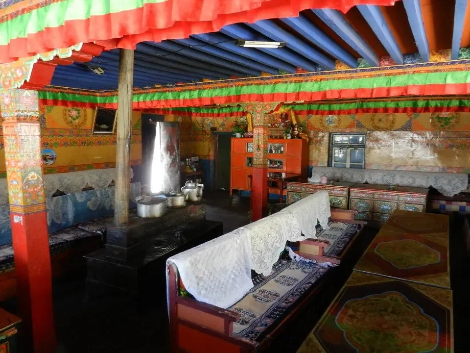 Interno di una locanda monastica con letti decorati in un ambiente alpino.