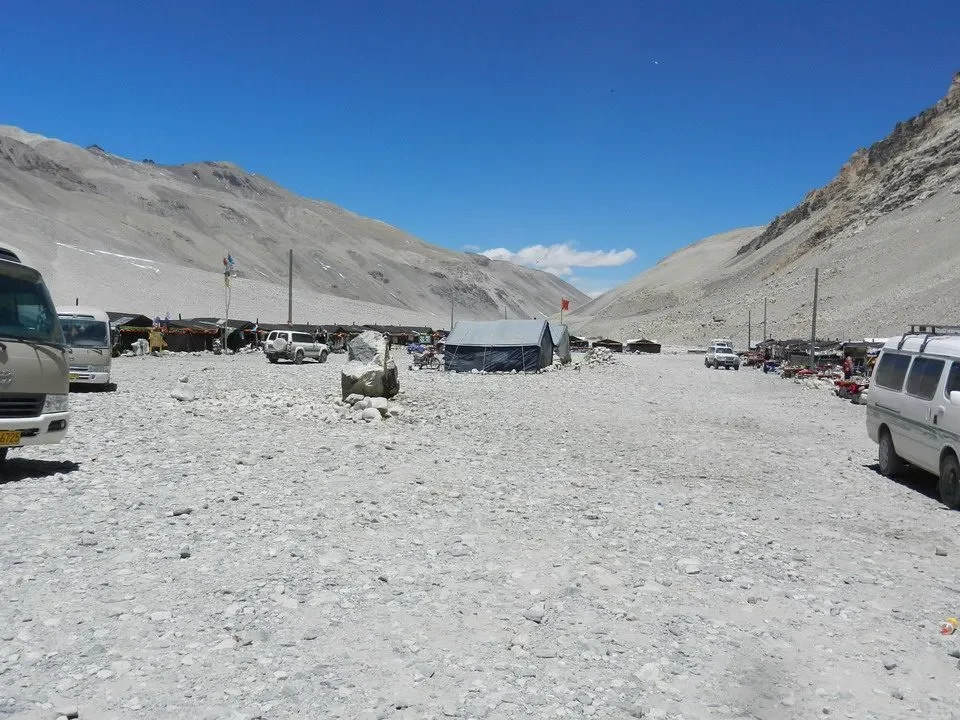 Un campo di tende si estende su un paesaggio montano alpino in Nepal o Tibet.