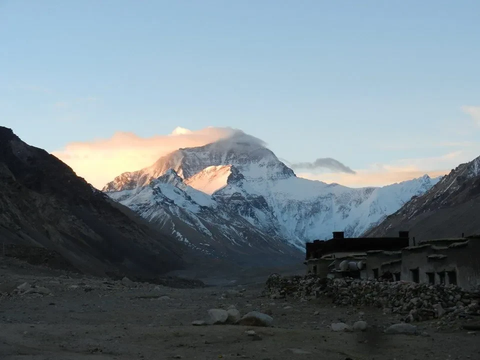 Paesaggio montano al tramonto con l'Everest visibile in lontananza.
