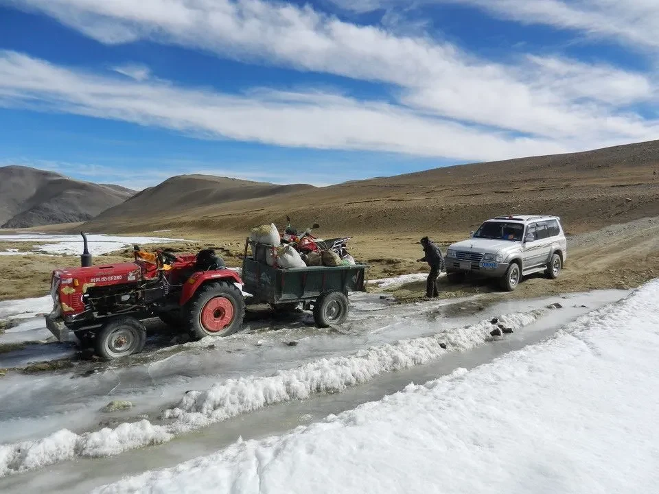 Un veicolo attraversa un sentiero innevato in un paesaggio montano del Nepal o del Tibet.
