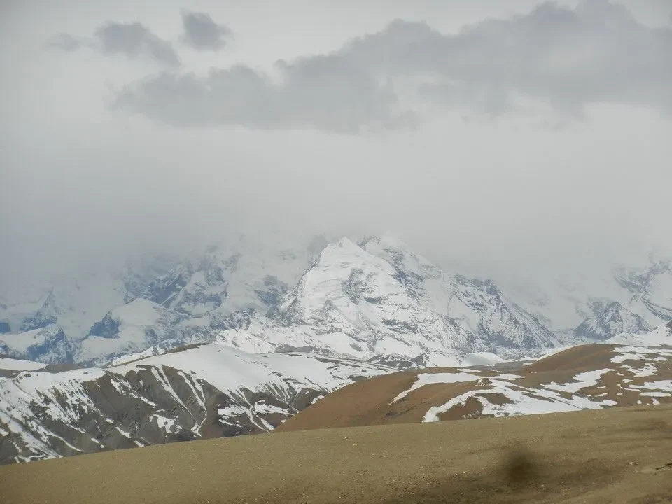 Paesaggio montano innevato con montagne imponenti sotto un cielo nuvoloso.